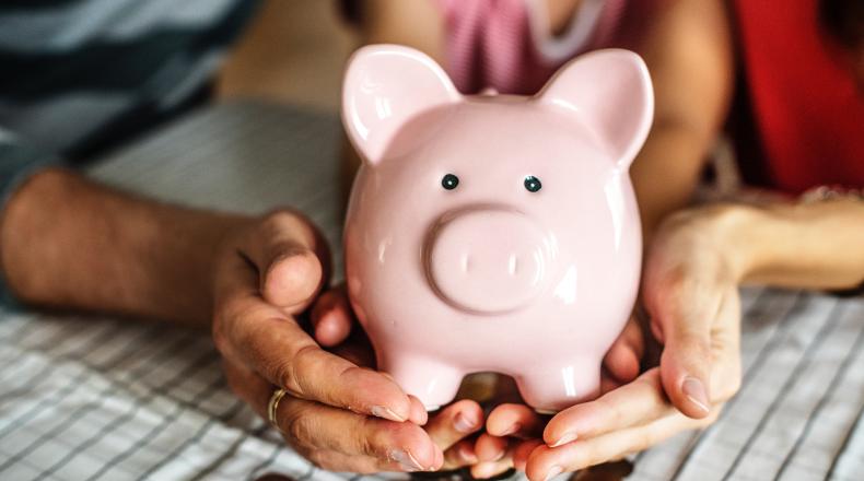 hands of three people holding a piggy bank