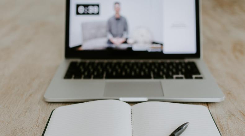 notepad and pen in front of opened laptop