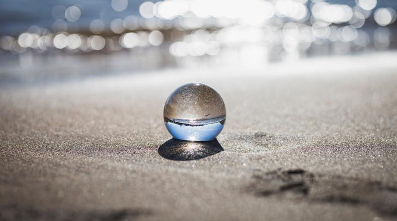 clear glass ball sitting on sand