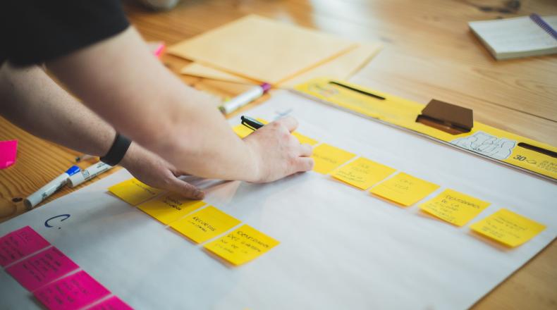 person writing on yellow notes on white paper