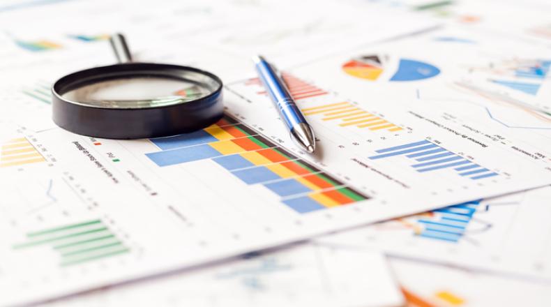 magnifying glass and pen on financial charts and graphs