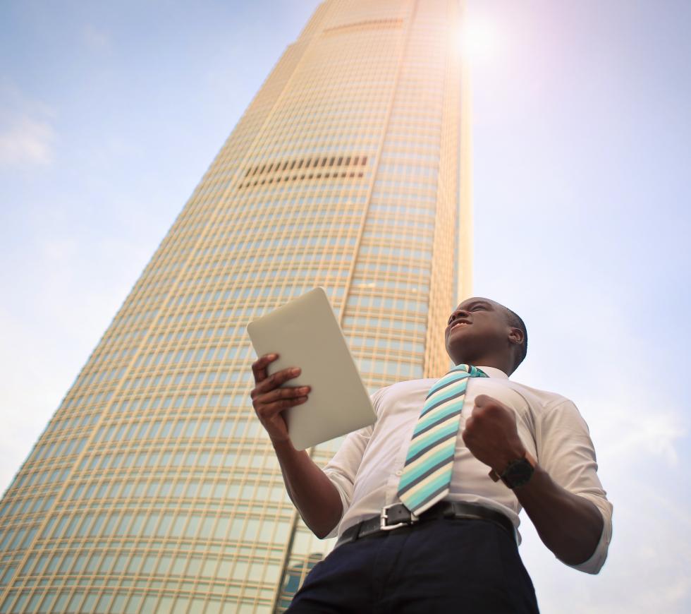 African American male holding tablet in one hand, smiling and looking upward