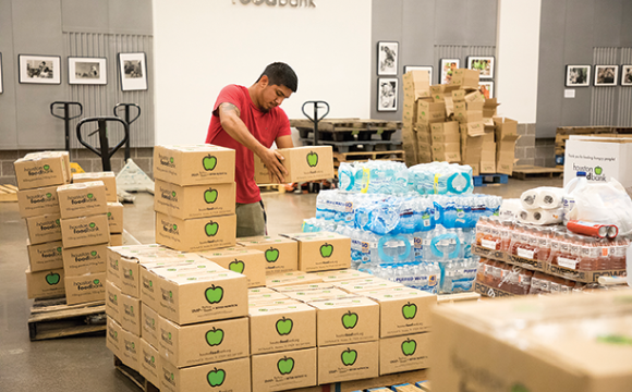 Man stacking boxes of supplies for hurricane victims in a warehouse.