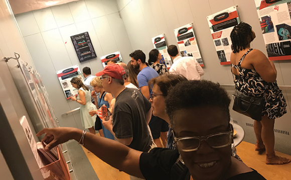 People looking at posters on at the pop-up AR Exhibit, Black Broadway on U: Echoes of an Era at the Studio Theatre in Washington, D.C.