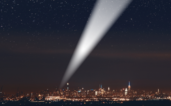 Cityscape at night with a beam of light shooting into the sky