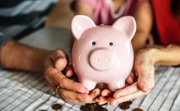 hands of three people holding a piggy bank