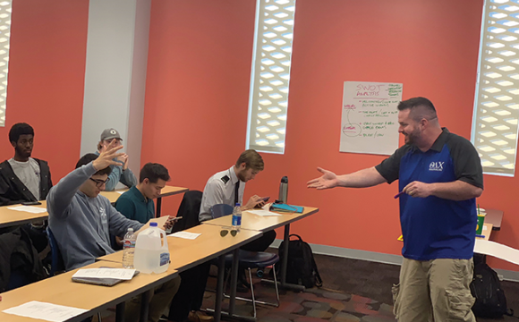 teacher in the front of a class interacting with students