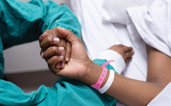 doctor holding the hand of a patient laying in a hospital bed