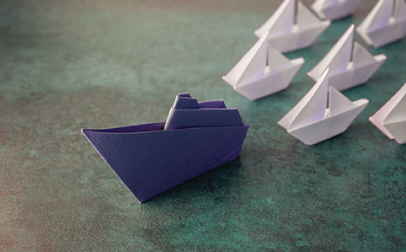 bllue paper boat in front of smaller white boats