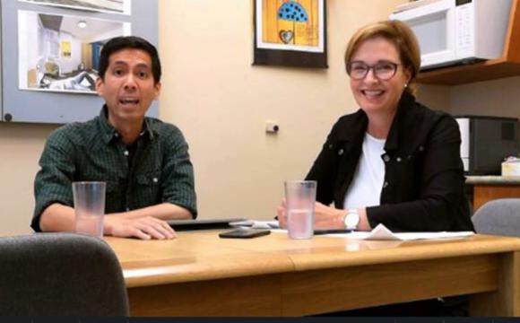 a man and a woman sitting at a table talking and smiling