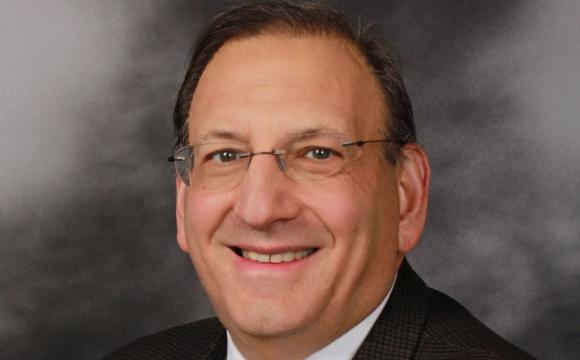 man wearing glasses and a suit smiling at camera