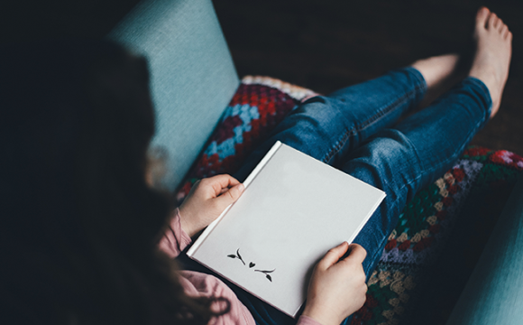 woman sitting on a couch reading a book