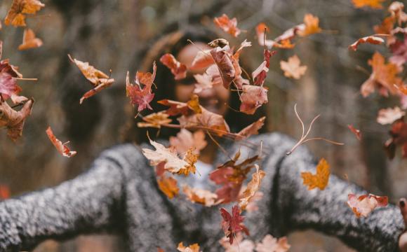 woman throwing leaves in air