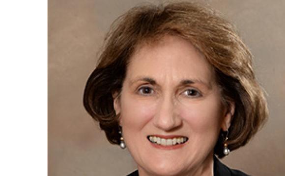 woman wearing blue top and black jacket smiling at the camera