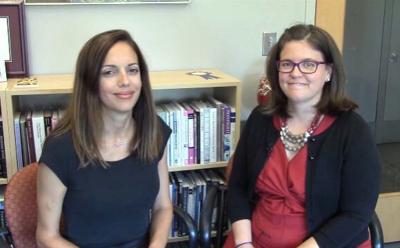 two women sitting in an office smiling at the camera