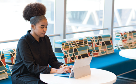 girl sitting at a table working on a laptop