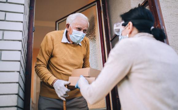 young female volunteer in a mask with an elderly man in a mask