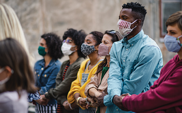 diverse men and women holding hands wearing masks