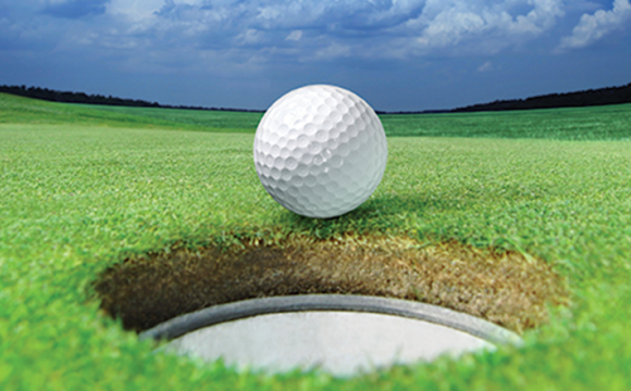 golf ball at a hole in the golf course with a blue sky