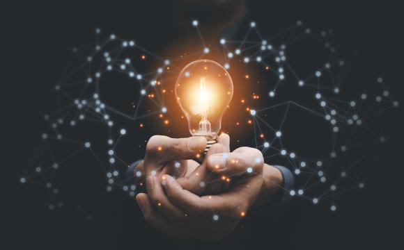 business hand holding a light bulb with a black background