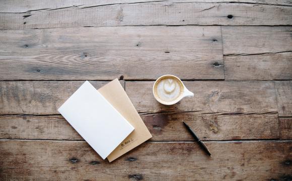 wood table with paper, pen and a coffee