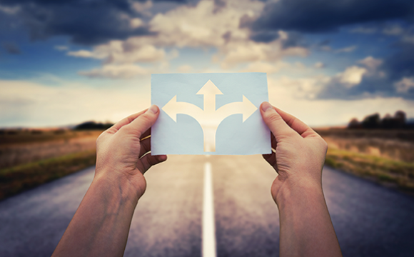 hands holding a paper with three arrows over a road in different directions