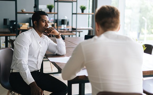 pensive serious man sitting with a man at a table