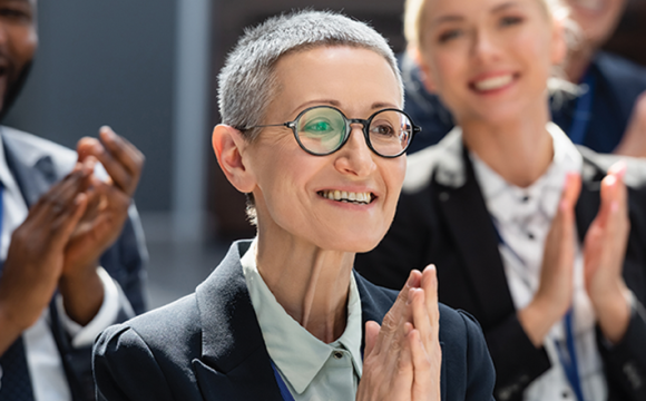 woman smiling and clapping with a crowd clapping around her