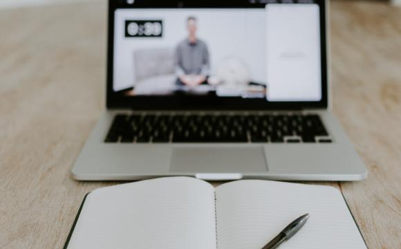 notepad and pen in front of opened laptop