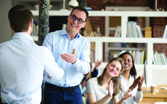 business men shaking hands with people clapping