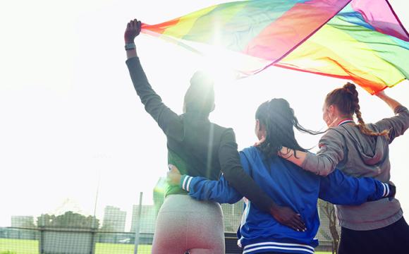 three women holding a lgbtqia flag