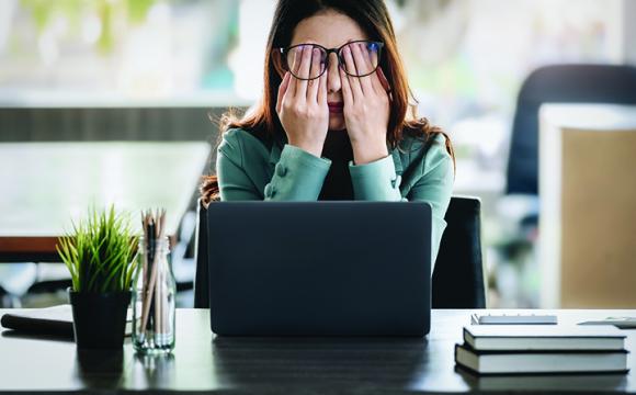 woman in an office rubbing her eyes