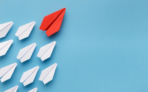 white paper airplanes with a red plane leading the group