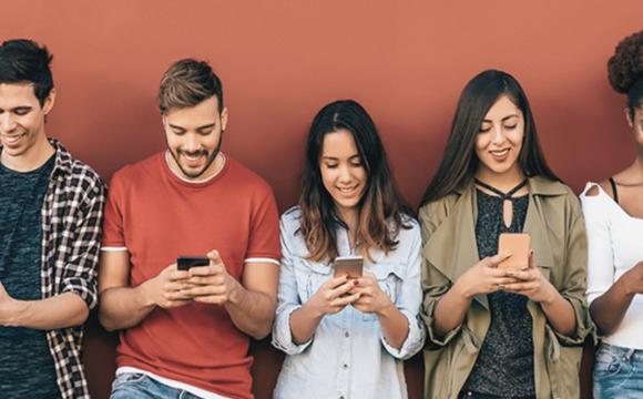 young generation leaning up against a wall looking at their phones