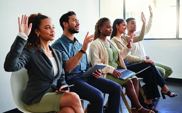 group of people sitting in a line with their hands raised