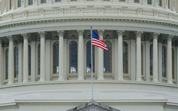 a U.S. flag waves in front of the U.S. Capitol building